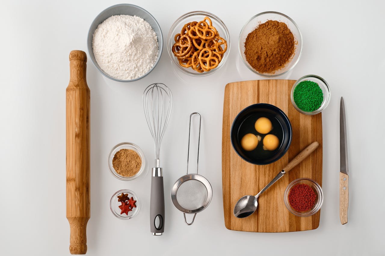 Flat lay of baking ingredients including flour, eggs, pretzels, and sprinkles for dessert preparation.